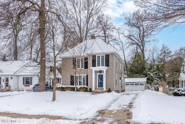 colonial inspired home featuring an outdoor structure, a chimney, and a detached garage