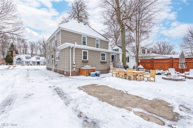 snow covered rear of property featuring an outdoor fire pit and fence