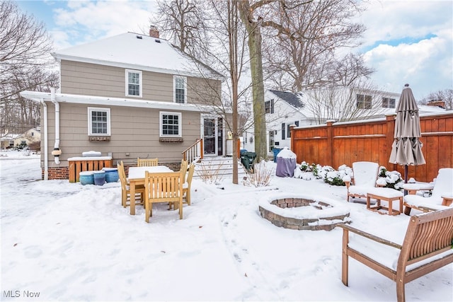 snow covered property with a fire pit and fence