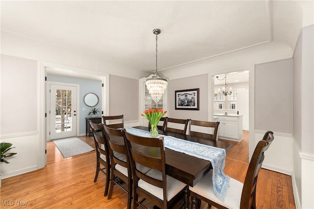 dining area with baseboards, light wood-style flooring, and an inviting chandelier