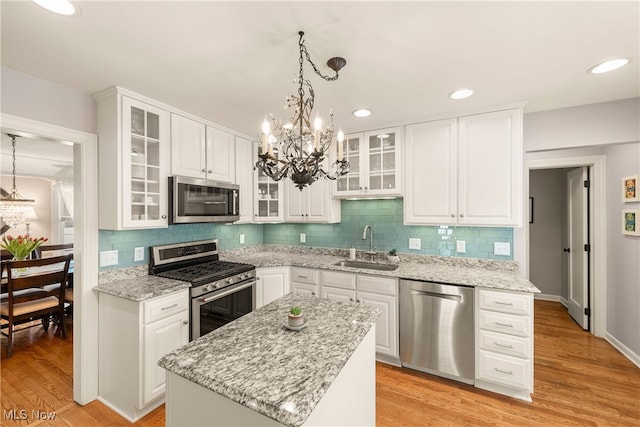 kitchen featuring appliances with stainless steel finishes, light wood-type flooring, white cabinets, and a sink