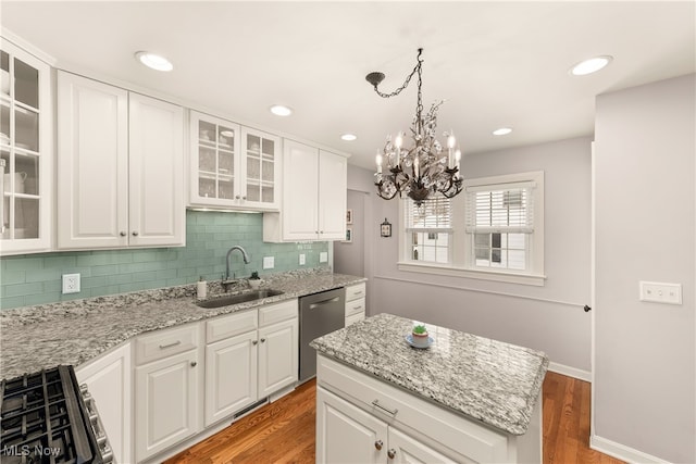 kitchen with decorative backsplash, dishwasher, light wood finished floors, and a sink