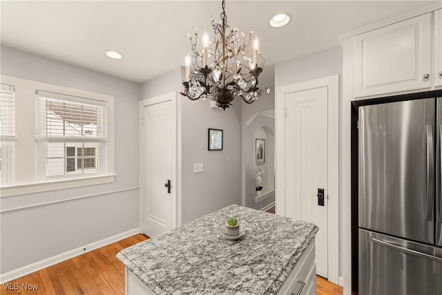 kitchen featuring light wood-type flooring, freestanding refrigerator, white cabinets, and recessed lighting