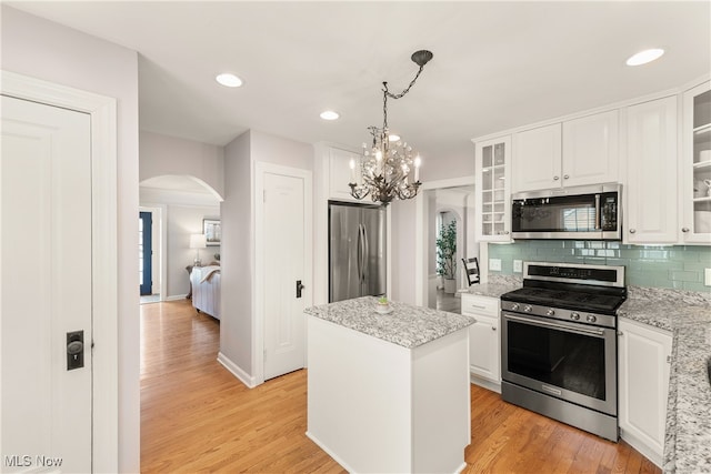 kitchen with white cabinetry, appliances with stainless steel finishes, arched walkways, and light wood-style flooring