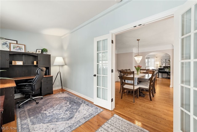 office with arched walkways, french doors, light wood-style flooring, and baseboards