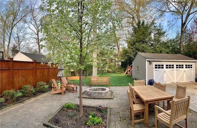 view of patio / terrace with a fire pit, an outbuilding, fence, and a detached garage