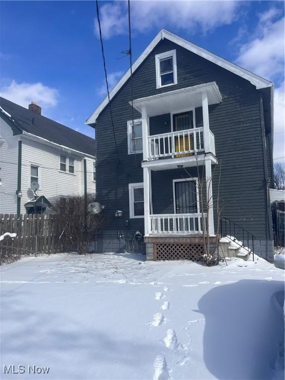 view of front of house featuring a balcony and fence