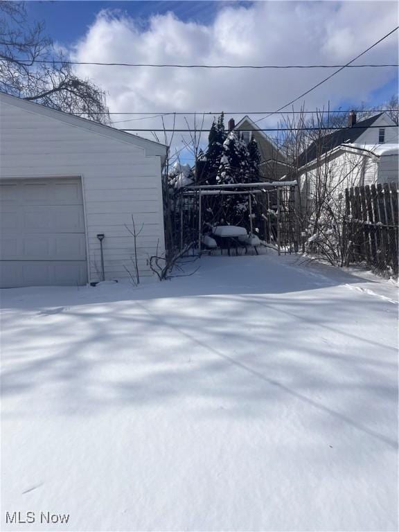 yard layered in snow with a garage and an outdoor structure