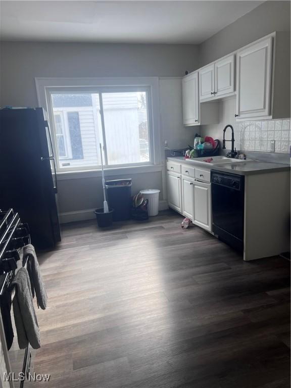 kitchen with a wealth of natural light, white cabinets, black appliances, and a sink