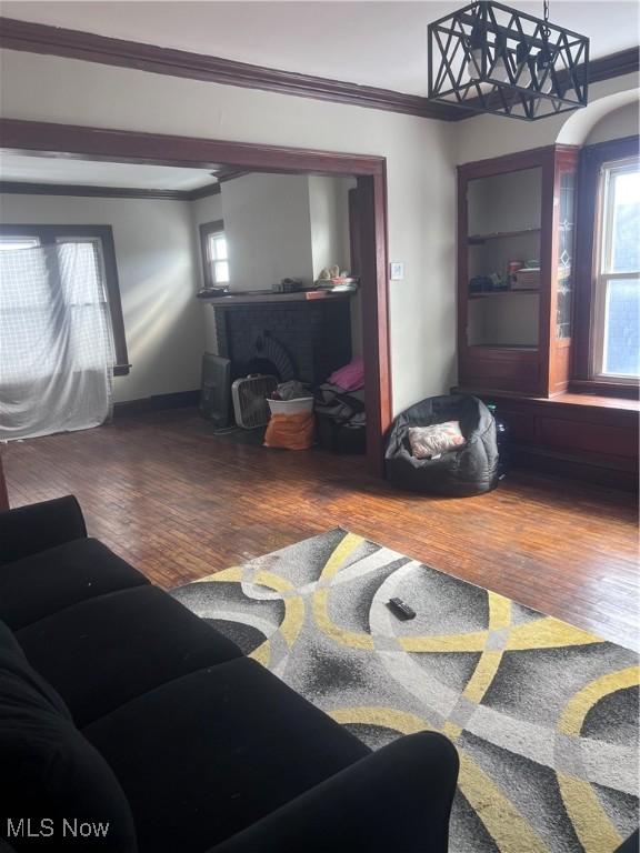 living room with a fireplace, crown molding, and wood finished floors