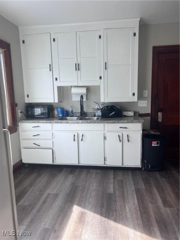 kitchen with black microwave, white cabinetry, and a sink