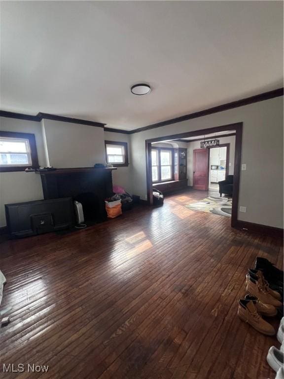 unfurnished living room with dark wood-type flooring, baseboards, and ornamental molding