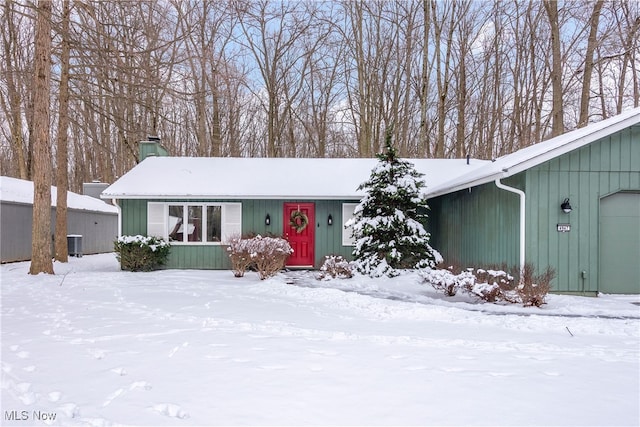 view of front of house with a garage, a chimney, and cooling unit