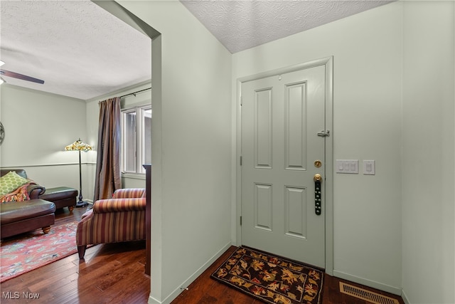 entrance foyer featuring a ceiling fan, visible vents, a textured ceiling, and wood finished floors