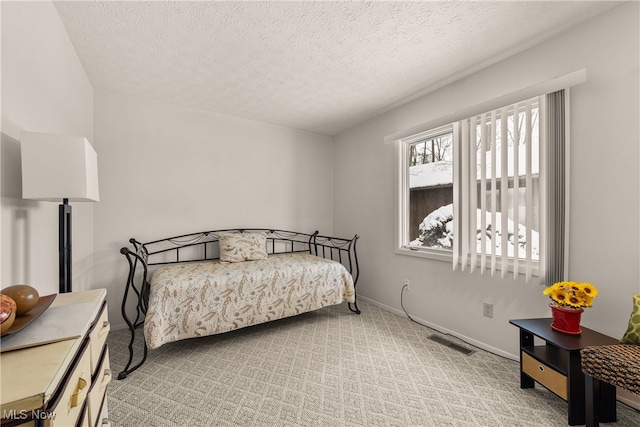 bedroom featuring light colored carpet, visible vents, a textured ceiling, and baseboards