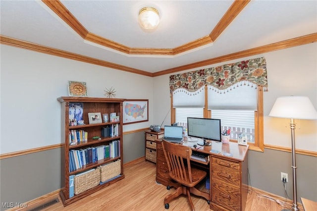 office featuring baseboards, ornamental molding, light wood-style floors, and a tray ceiling