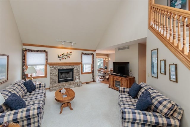 carpeted living room featuring stairs, an inviting chandelier, rail lighting, a fireplace, and visible vents