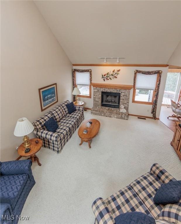 carpeted living room with visible vents, rail lighting, vaulted ceiling, and a fireplace