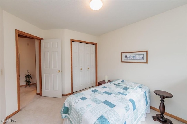 bedroom with a closet, light carpet, and baseboards