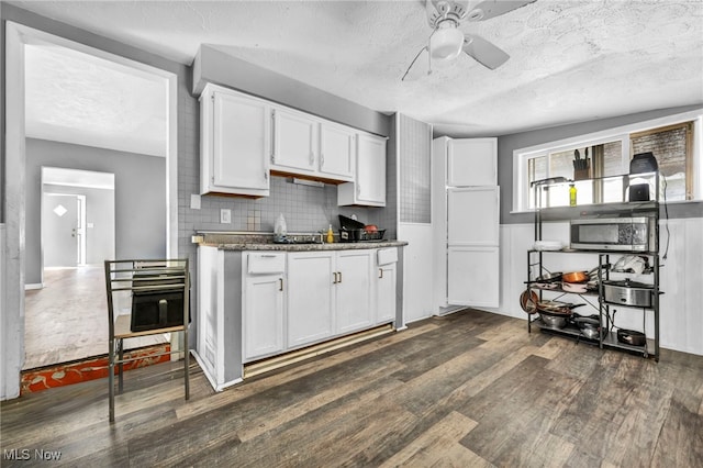 kitchen with white cabinetry, dark stone countertops, and dark hardwood / wood-style floors