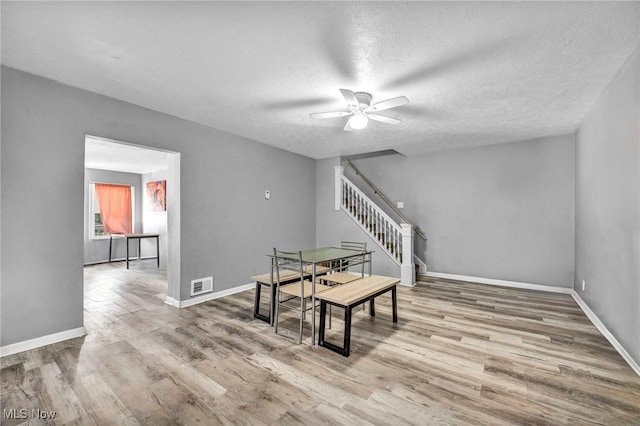 dining area with a textured ceiling, light wood-type flooring, and ceiling fan