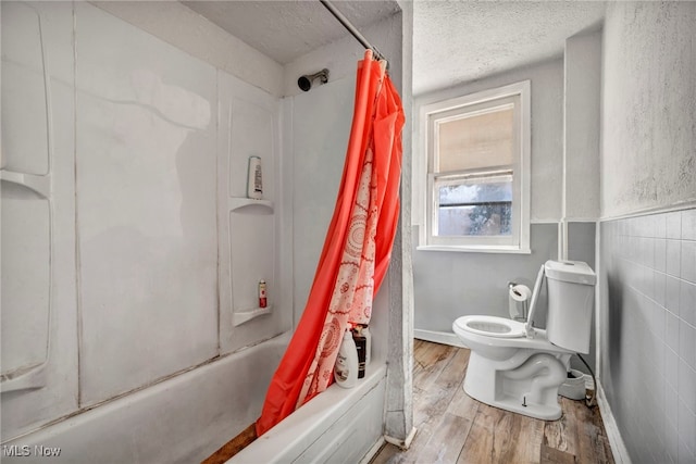 bathroom featuring shower / bath combination with curtain, tile walls, toilet, hardwood / wood-style flooring, and a textured ceiling