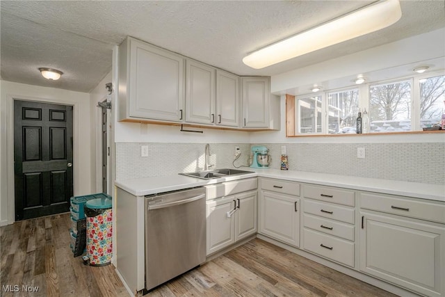 kitchen with sink, stainless steel dishwasher, white cabinetry, and light hardwood / wood-style floors