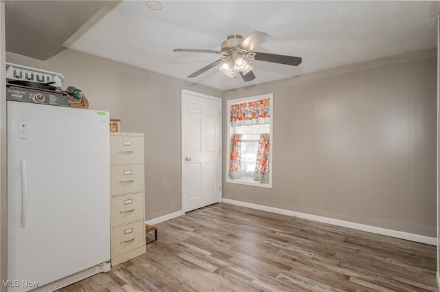 unfurnished bedroom featuring ceiling fan, hardwood / wood-style flooring, and white refrigerator