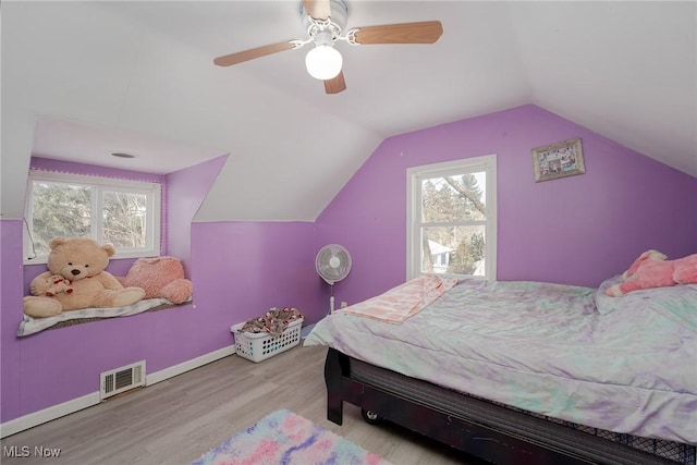 bedroom with ceiling fan, vaulted ceiling, multiple windows, and light hardwood / wood-style flooring