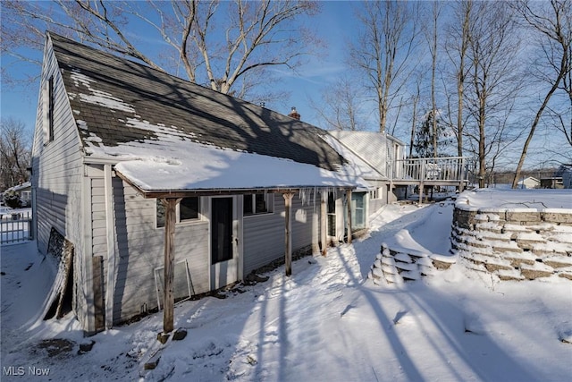 snow covered rear of property with a deck