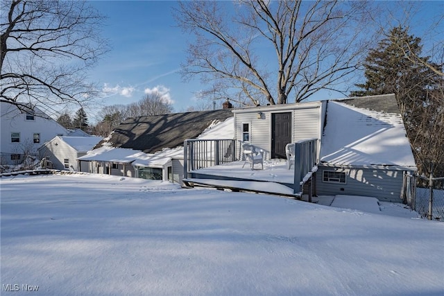 snow covered rear of property with a deck