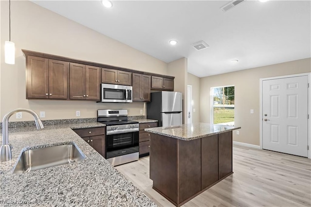 kitchen featuring visible vents, appliances with stainless steel finishes, light stone countertops, dark brown cabinets, and a sink