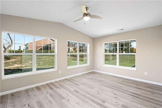 spare room with lofted ceiling, visible vents, light wood-style flooring, and baseboards