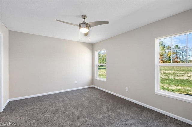 spare room featuring baseboards, dark colored carpet, and a ceiling fan