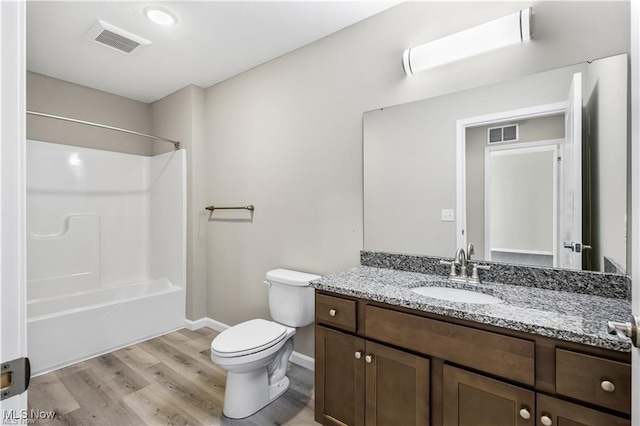 bathroom with toilet, vanity, wood finished floors, and visible vents