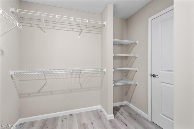 walk in closet with light wood-style floors