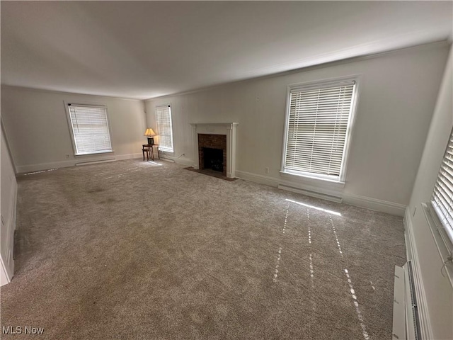 unfurnished living room featuring a fireplace with flush hearth, baseboards, and carpet