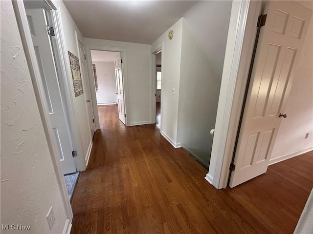 hallway featuring baseboards and dark wood-style floors