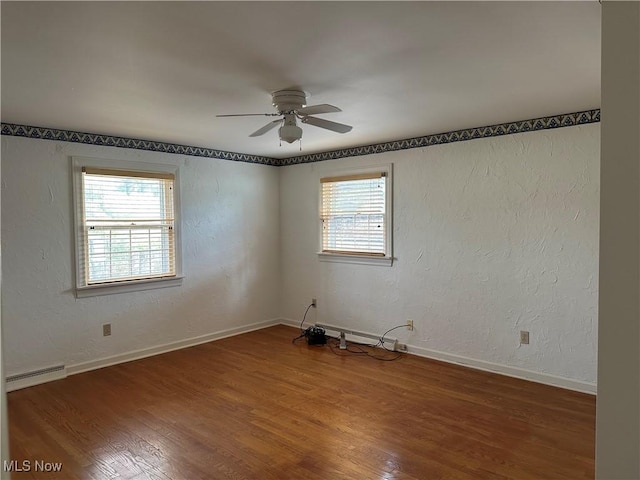 unfurnished room featuring baseboards, baseboard heating, a ceiling fan, and wood finished floors