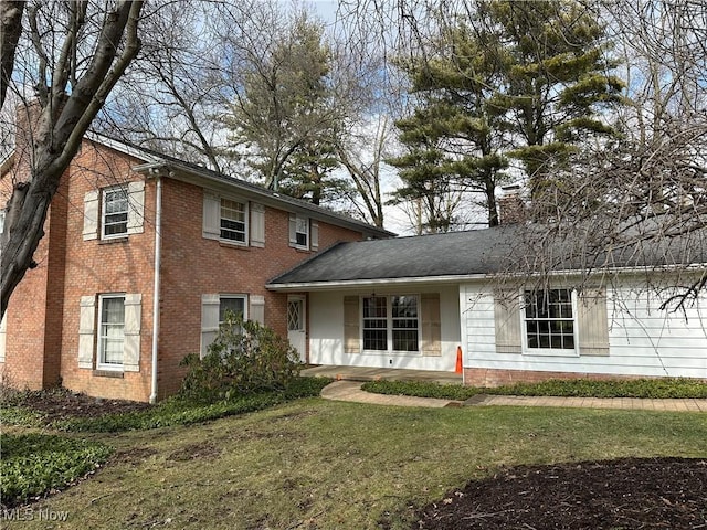 view of front of house featuring brick siding, a front yard, and a chimney