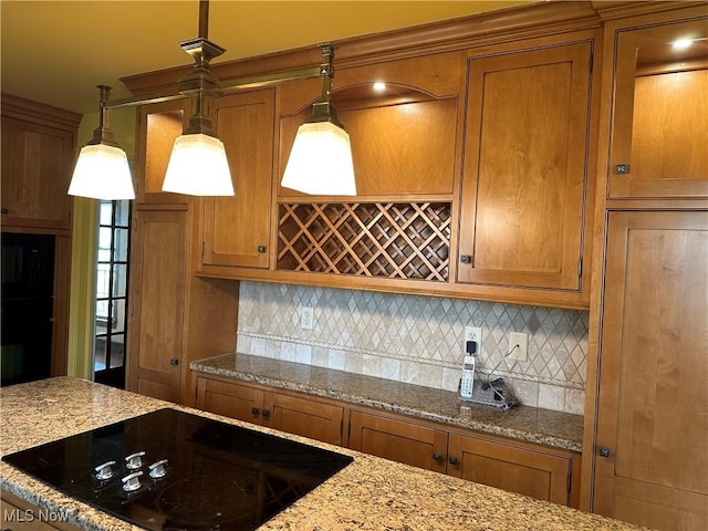 kitchen featuring decorative light fixtures, backsplash, black appliances, and brown cabinetry