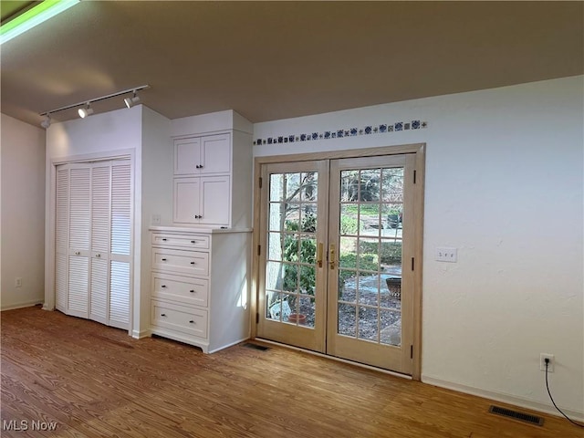 doorway to outside featuring baseboards, visible vents, french doors, and light wood finished floors