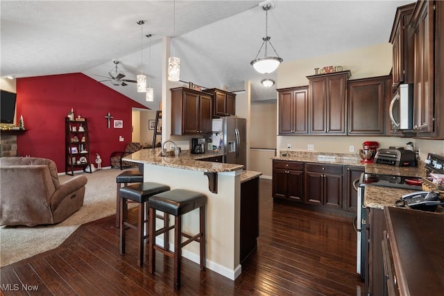 kitchen with open floor plan, stainless steel appliances, a breakfast bar area, and decorative light fixtures