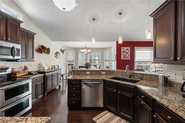 kitchen with stainless steel appliances, dark brown cabinets, a sink, and decorative light fixtures