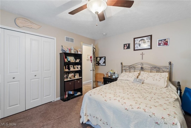 carpeted bedroom with ceiling fan, a textured ceiling, visible vents, baseboards, and a closet