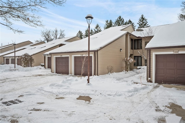 snow covered garage with a detached garage