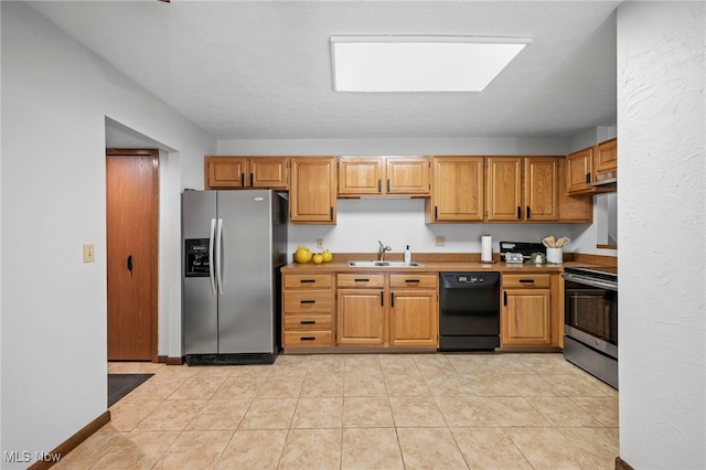 kitchen featuring light tile patterned floors, appliances with stainless steel finishes, a sink, and baseboards