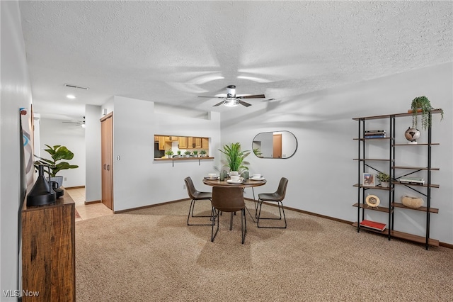 dining area with light carpet, a textured ceiling, and a ceiling fan