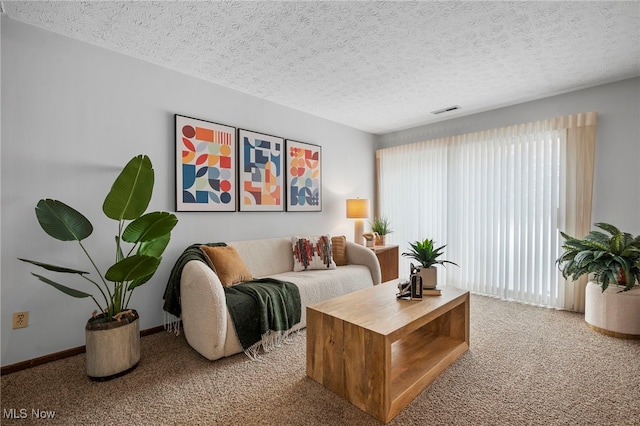 carpeted living room featuring baseboards, visible vents, and a textured ceiling