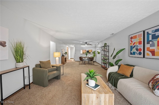 carpeted living room featuring visible vents, a ceiling fan, and a textured ceiling